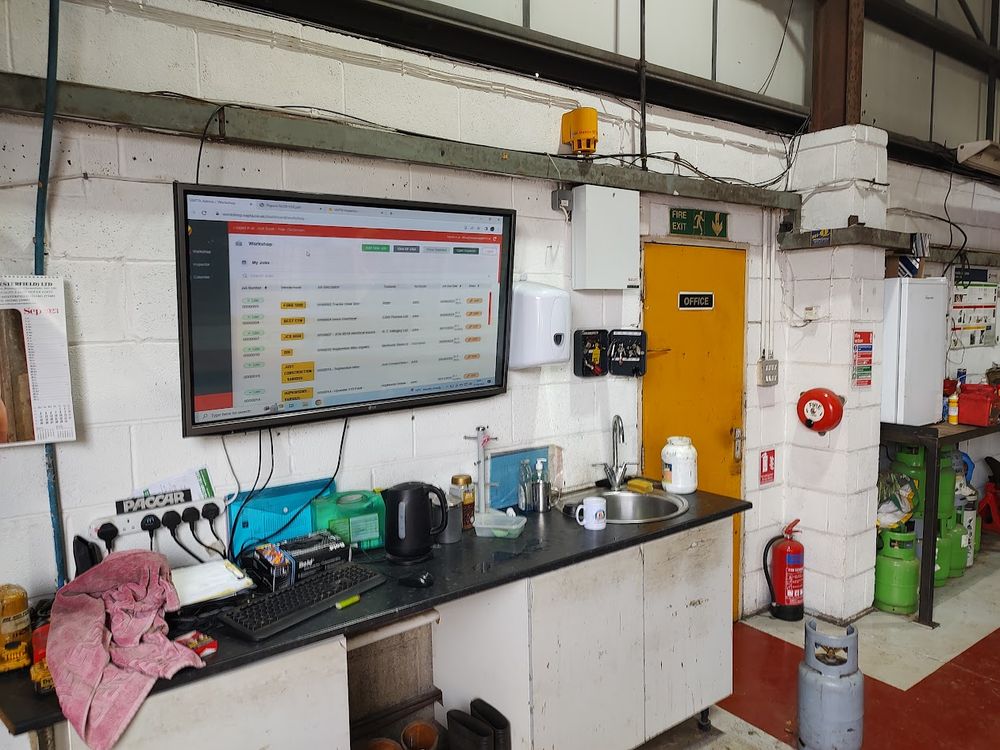 VAPTA workshop jobs board on a large screen in a commercial workshop