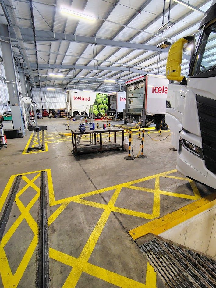 Modern commercial vehicle workshop with marked-out bays and delivery trucks
