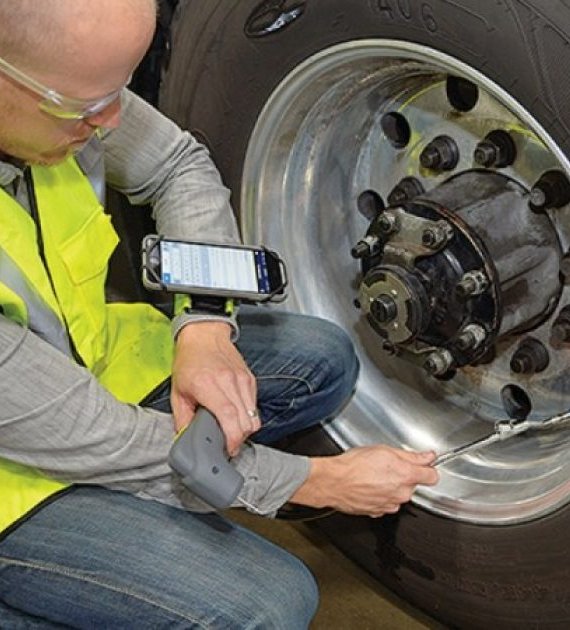 Technician carrying out a wheel torque check on an HGV with a handheld device